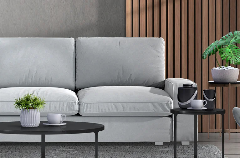 a white couch with a cup and a plant on a coffee table
